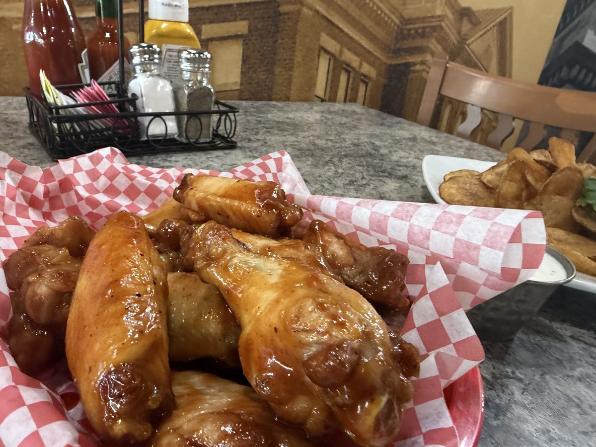 A basket of saucy bone-in wings with chips and ranch