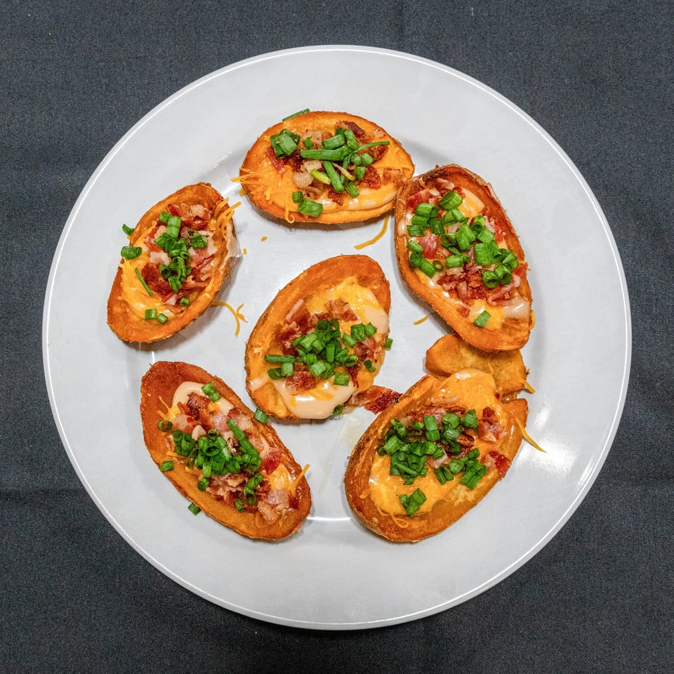 Plate of six toasted bread slices topped with melted cheese, bacon, and chopped green onions.